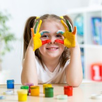 cute kid girl showing her hands painted in bright colors